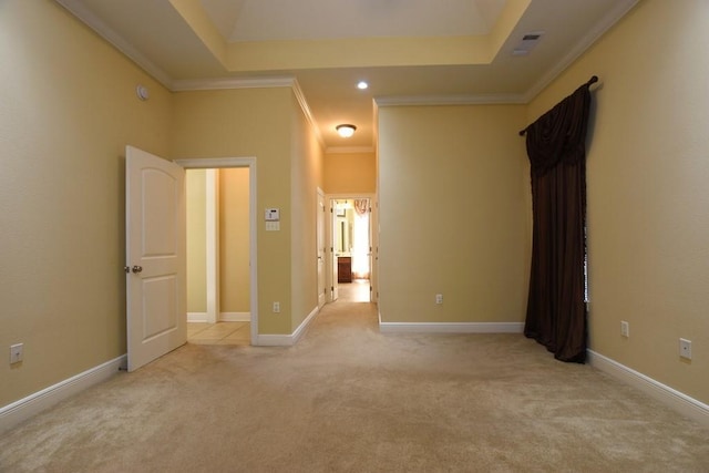 carpeted empty room featuring a tray ceiling and crown molding