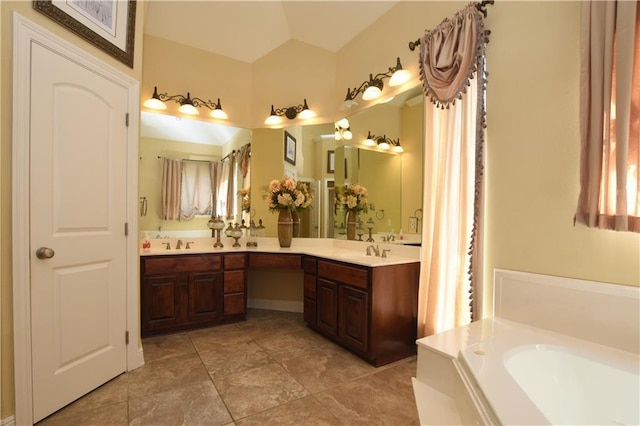 bathroom featuring lofted ceiling, vanity, tile patterned floors, and a washtub