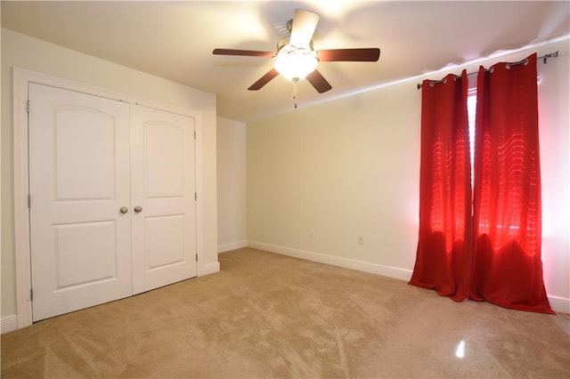 unfurnished bedroom featuring light carpet, a closet, and ceiling fan