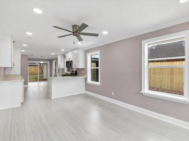 kitchen featuring light stone counters, appliances with stainless steel finishes, kitchen peninsula, ceiling fan, and white cabinets