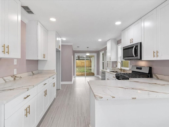 kitchen featuring sink, light hardwood / wood-style flooring, white cabinetry, stainless steel appliances, and light stone counters