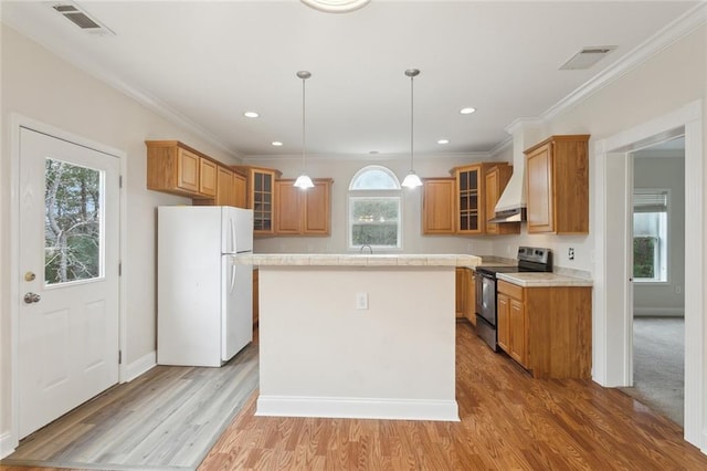 kitchen featuring stainless steel electric range oven, decorative light fixtures, a center island, white fridge, and light hardwood / wood-style floors