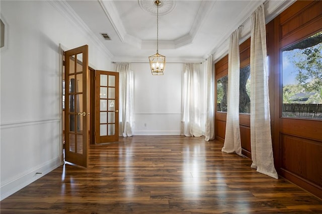 unfurnished dining area featuring an inviting chandelier, dark wood-type flooring, ornamental molding, and a raised ceiling