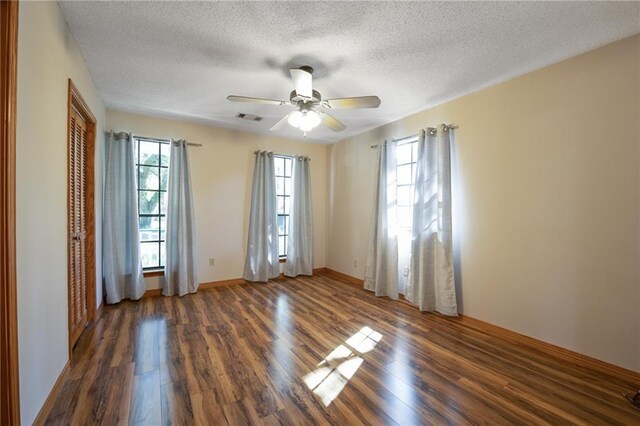 empty room featuring ceiling fan, a textured ceiling, and dark hardwood / wood-style flooring