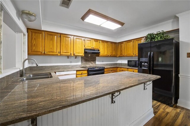 kitchen with dark wood-type flooring, a kitchen bar, sink, kitchen peninsula, and black appliances