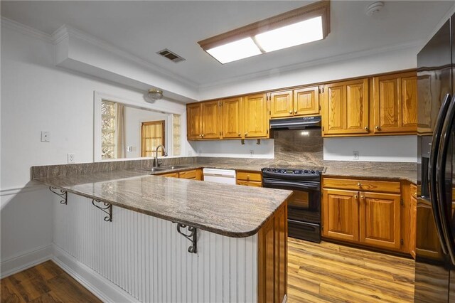 kitchen featuring sink, kitchen peninsula, light wood-type flooring, and black appliances