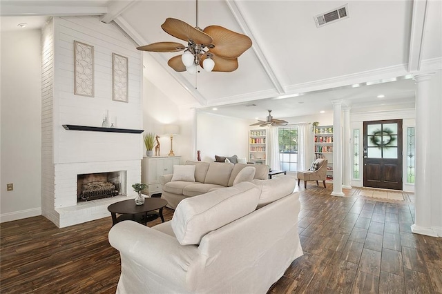 living room featuring a fireplace, dark hardwood / wood-style floors, beamed ceiling, and ornate columns