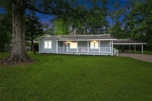 view of front of property featuring driveway, covered porch, an attached carport, and a front yard