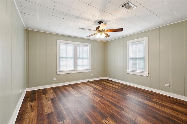 unfurnished room featuring dark wood-type flooring, visible vents, and baseboards