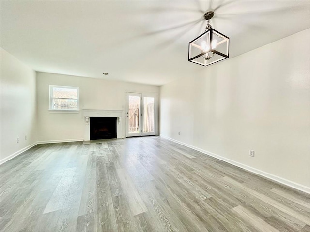 unfurnished living room featuring hardwood / wood-style flooring, a healthy amount of sunlight, and an inviting chandelier