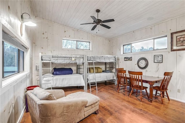 bedroom featuring wooden ceiling, vaulted ceiling, wooden walls, and wood finished floors