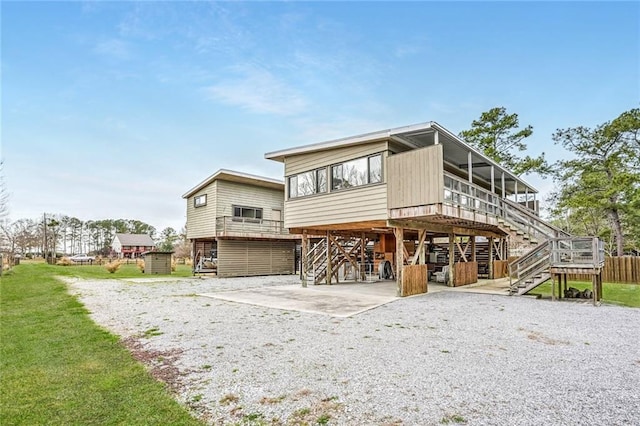 back of house with a carport, a yard, driveway, and stairway