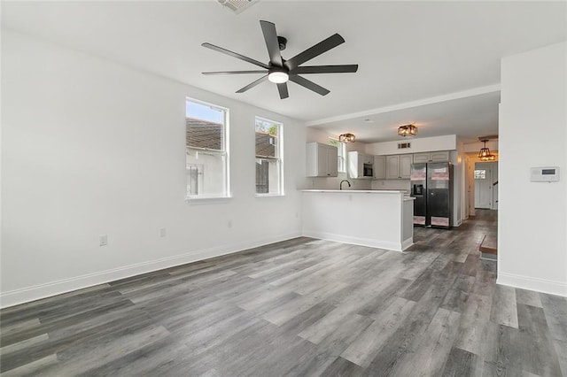 unfurnished living room featuring ceiling fan, dark wood-type flooring, and sink