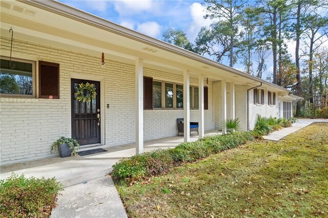 view of exterior entry with a yard and a porch