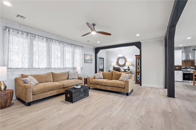 living room with crown molding, ceiling fan, and light wood-type flooring