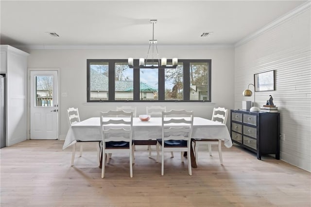 dining space featuring ornamental molding, a chandelier, and light hardwood / wood-style flooring