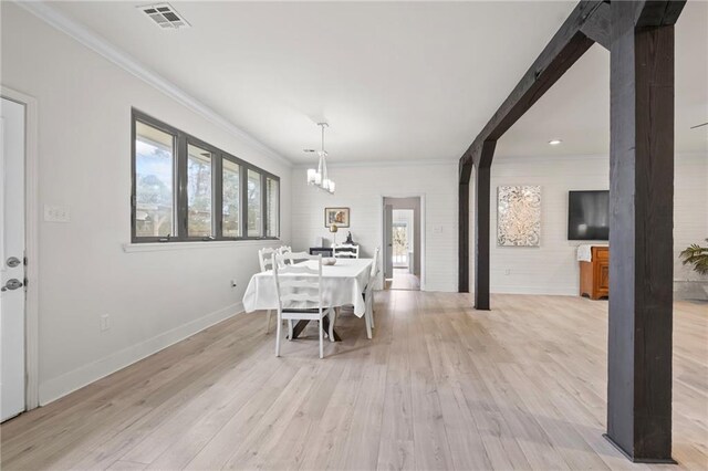 dining space with light hardwood / wood-style flooring, ornamental molding, and a chandelier