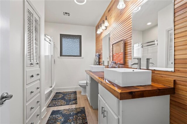 bathroom with toilet, hardwood / wood-style floors, vanity, and a shower with shower door