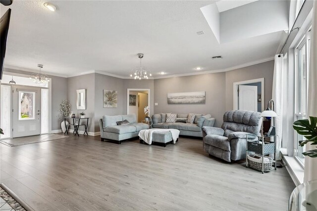 living room with crown molding, light hardwood / wood-style flooring, and a notable chandelier