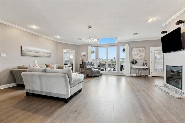 living room featuring wood-type flooring, ornamental molding, and a notable chandelier