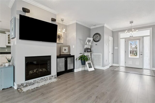 living room with crown molding, a chandelier, and light wood-type flooring