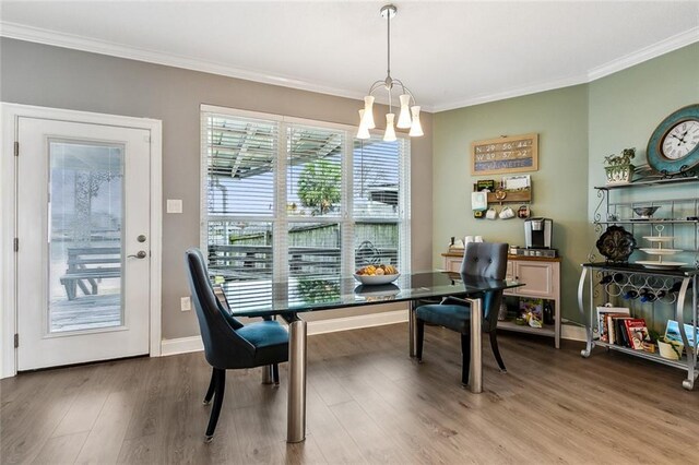 dining room with ornamental molding, wood-type flooring, and a notable chandelier