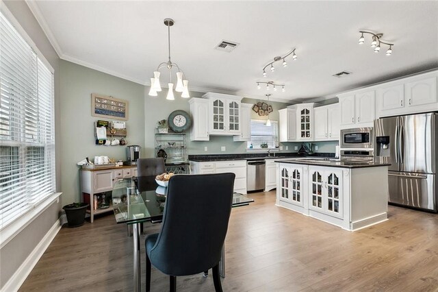 kitchen with white cabinetry, decorative light fixtures, a center island, appliances with stainless steel finishes, and a notable chandelier