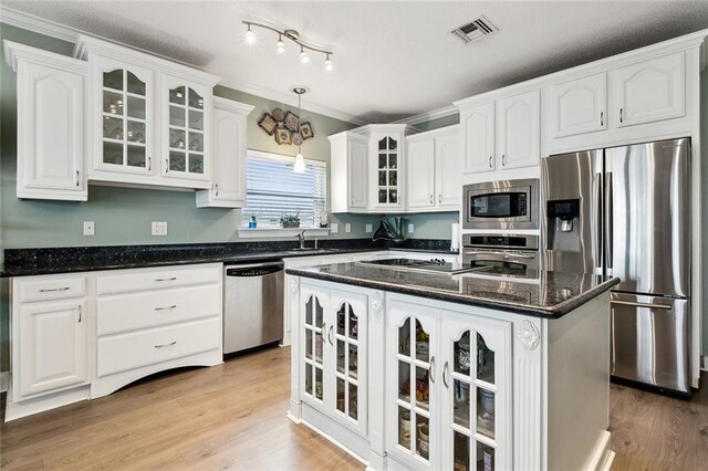 kitchen featuring pendant lighting, dark stone countertops, stainless steel appliances, white cabinets, and a kitchen island