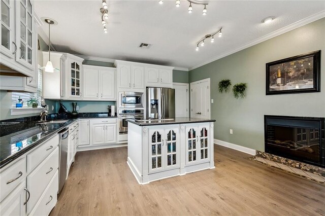 kitchen with appliances with stainless steel finishes, decorative light fixtures, light hardwood / wood-style flooring, and white cabinets