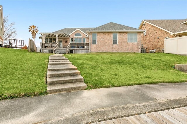 view of front of home featuring a front yard, a deck, and cooling unit