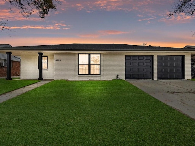 ranch-style house featuring a garage and a lawn