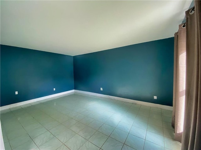 empty room with lofted ceiling and light tile patterned floors