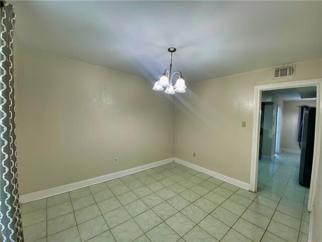 tiled empty room featuring a notable chandelier