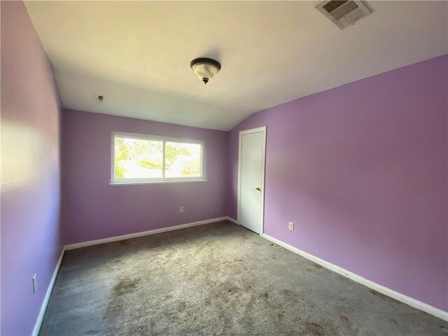 carpeted empty room featuring vaulted ceiling