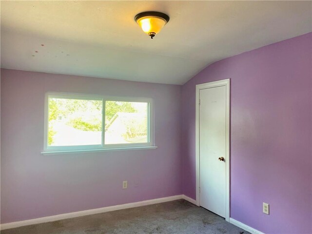 carpeted spare room featuring vaulted ceiling