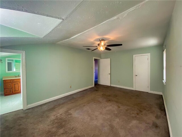 unfurnished bedroom featuring lofted ceiling, ceiling fan, a textured ceiling, and dark colored carpet