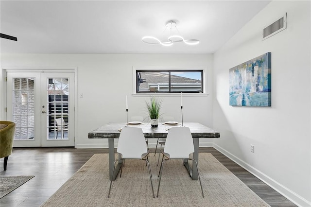 dining area featuring dark wood-type flooring, a chandelier, and french doors