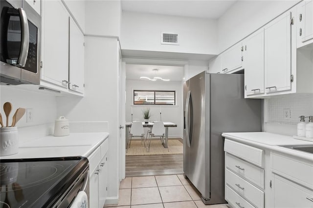 kitchen featuring tasteful backsplash, light tile patterned flooring, white cabinets, and appliances with stainless steel finishes