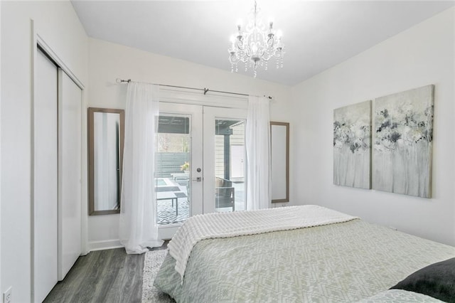 bedroom featuring french doors, a chandelier, access to outside, dark wood-type flooring, and a closet