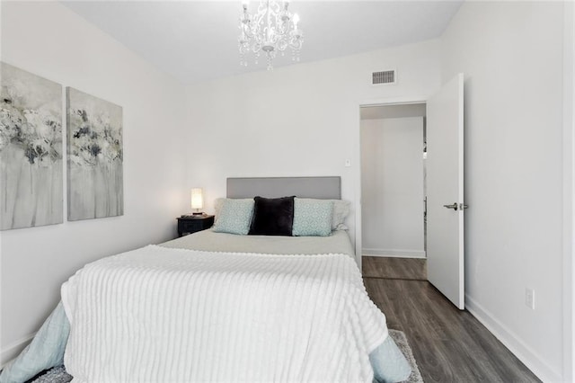 bedroom featuring an inviting chandelier and dark wood-type flooring