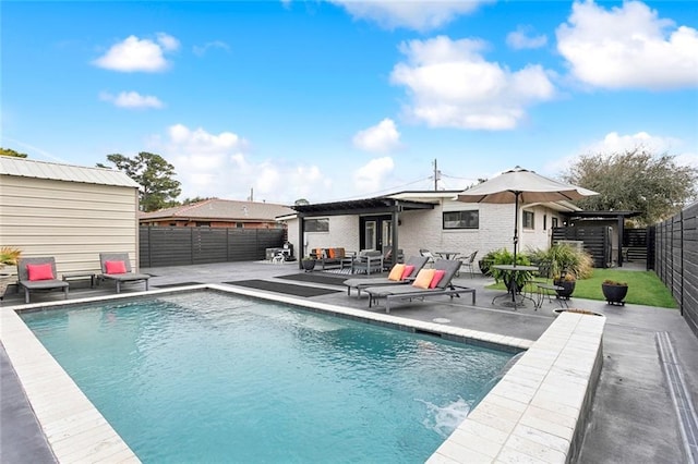 rear view of house with a fenced in pool, a patio, and a storage unit