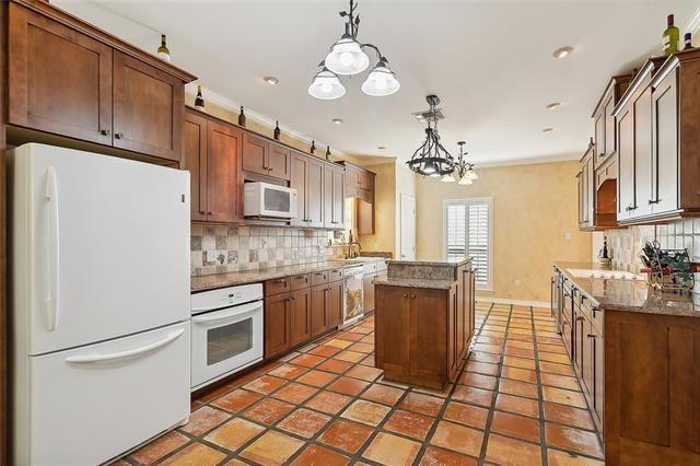 kitchen featuring pendant lighting, white appliances, decorative backsplash, and a center island