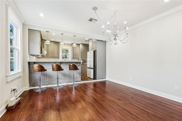 kitchen featuring an inviting chandelier, dark hardwood / wood-style floors, a kitchen breakfast bar, and refrigerator