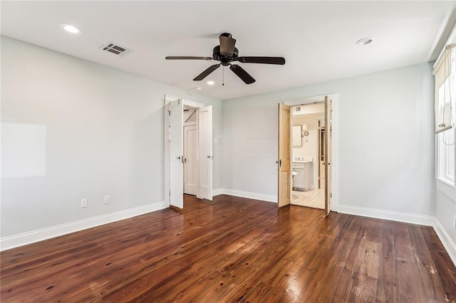 unfurnished bedroom featuring ensuite bath, dark wood-type flooring, and ceiling fan