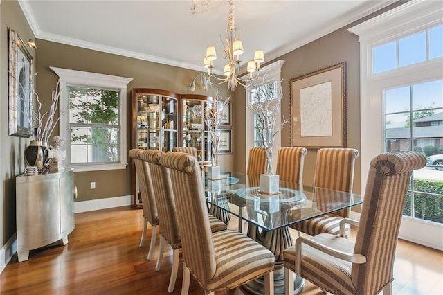 dining space with hardwood / wood-style flooring, ornamental molding, and a notable chandelier