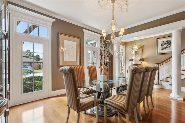 dining room featuring crown molding, light hardwood / wood-style flooring, decorative columns, and a chandelier