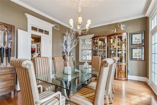 dining space with ornamental molding, light wood-type flooring, and a notable chandelier