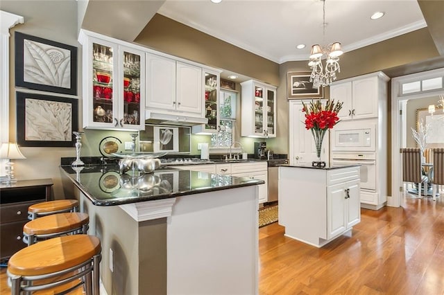 kitchen featuring white appliances, a kitchen bar, a center island, and white cabinets