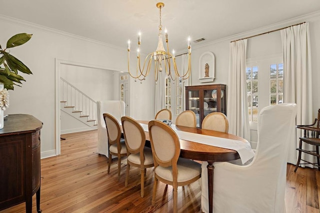 dining room with crown molding, a chandelier, and light wood-type flooring