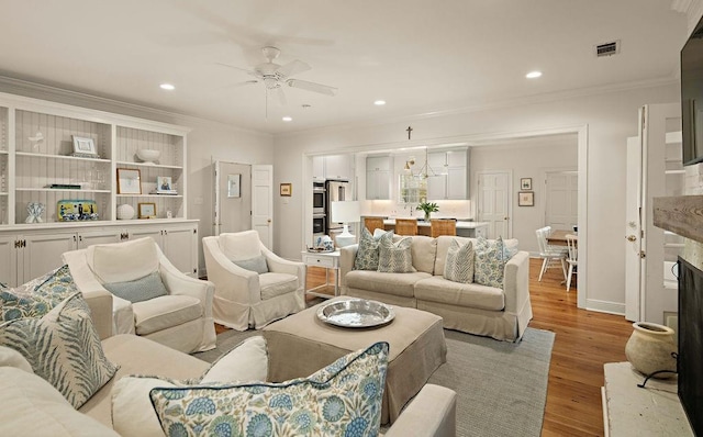 living room with ornamental molding, light hardwood / wood-style floors, and ceiling fan